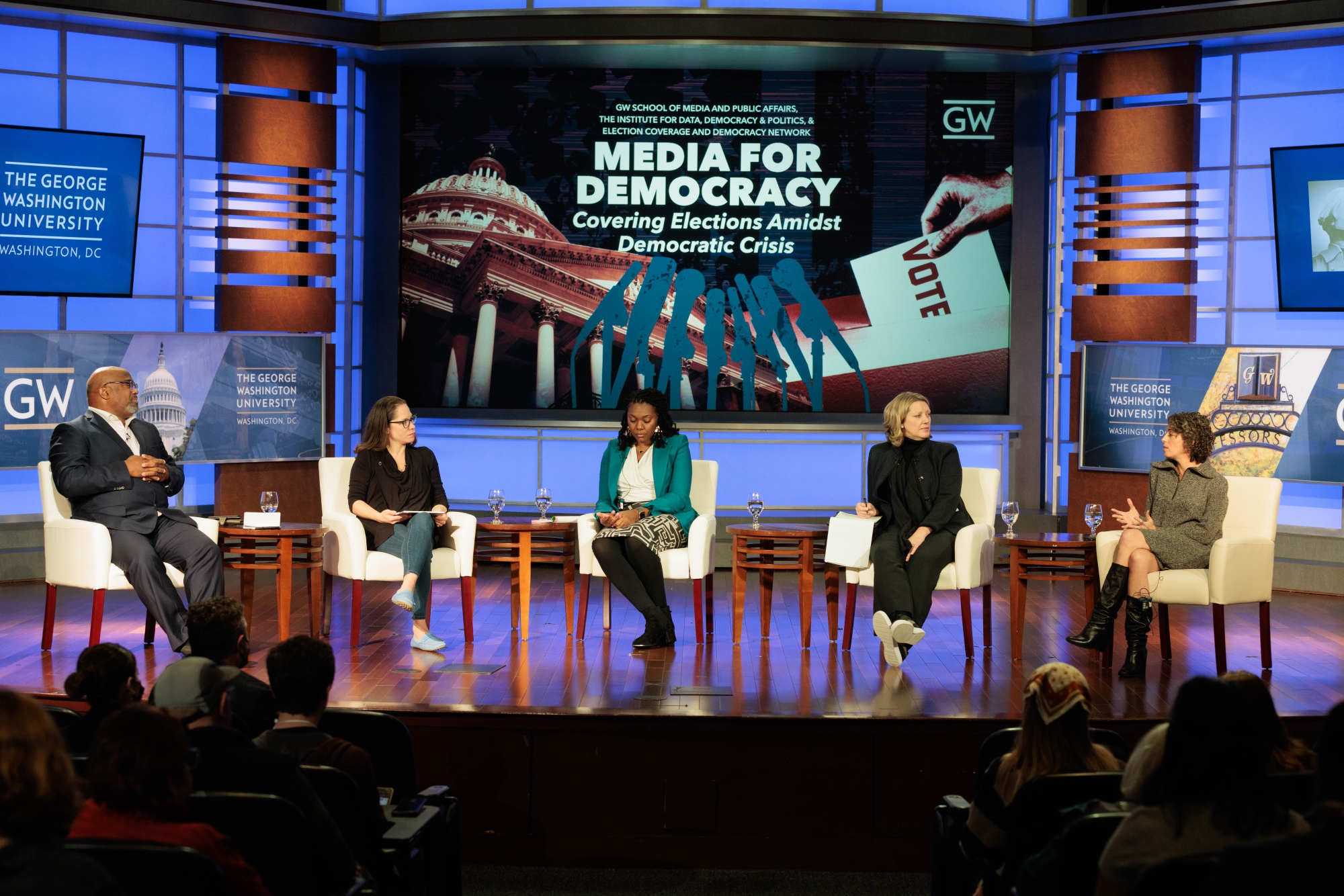 Panelists sitting on stage listening to a question from the moderator